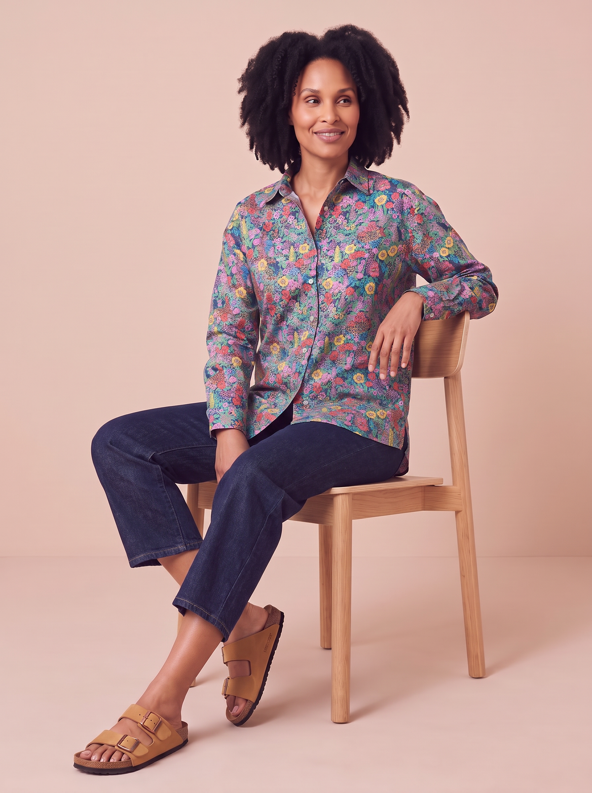 Chemise Christie Ciara portée, assise sur une chaise, jean brut et Birkenstock
