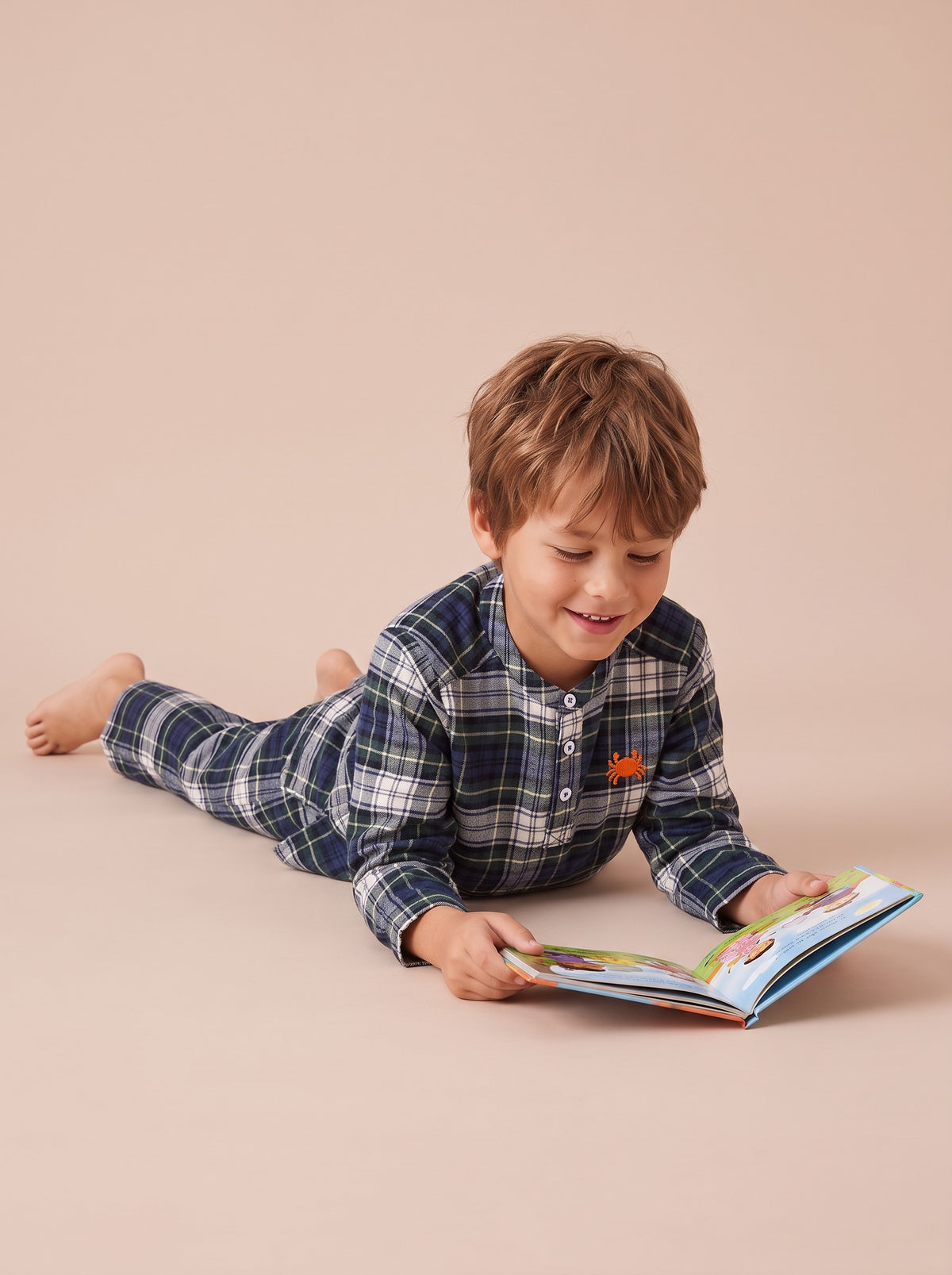 Pyjama en pilou à carreaux verts porté par un petit garçon allongé qui lit
