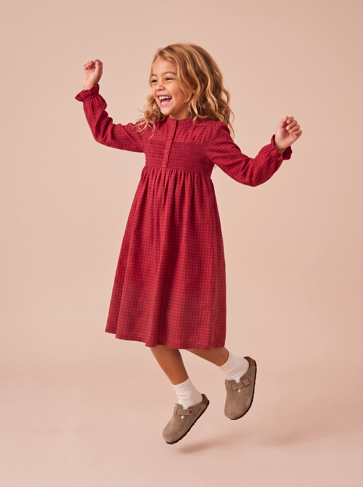Robe Harper rouge à carreaux portée par une petite fille qui saute de joie